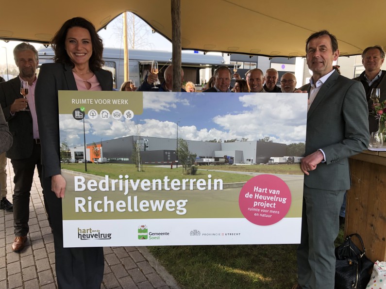 Gedeputeerde Rob van Muilekom en wethouder Nermina Kundić van de gemeente Soest houden een bord vast met een foto van bedrijventerrein Richelleweg