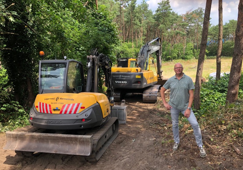 Robin Siebel poseert naast graafmachines