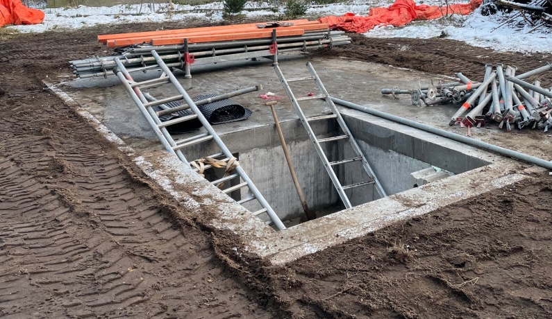 betonnen kelder op zandgrond met ladders en steigermateriaal